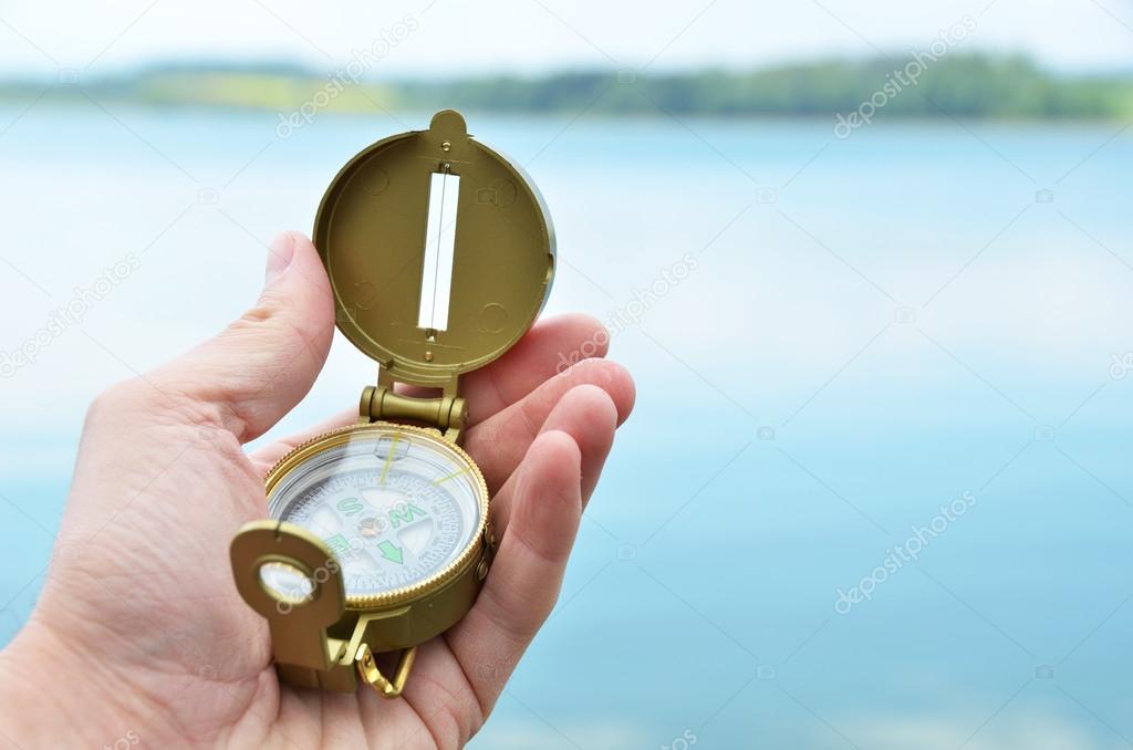 Compass in the hand against lake