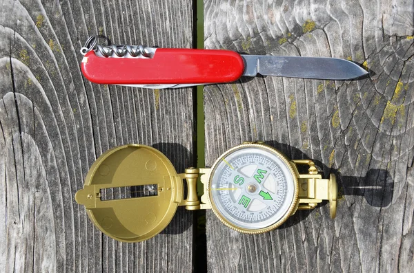 Compass and pocket knife on the wooden background — Stock Photo, Image