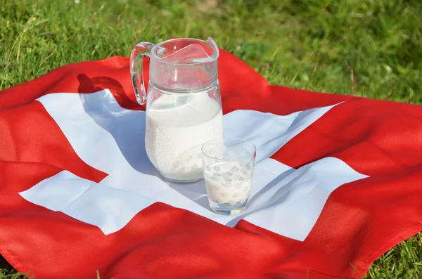 Caraffa di latte sulla bandiera svizzera . — Foto Stock