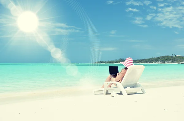 Meisje met een laptop op het tropisch strand — Stockfoto