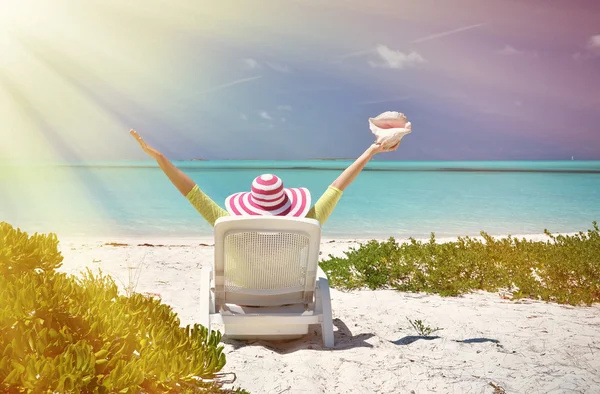 Menina com uma concha no leito de sol olhando para o oceano — Fotografia de Stock