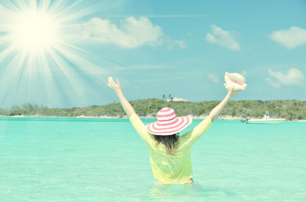 Девушка с раковиной на шезлонге смотрит на океан
