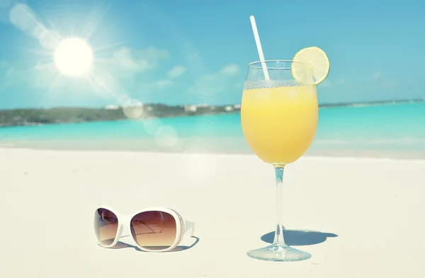 Jugo de naranja y gafas de sol en la playa — Foto de Stock