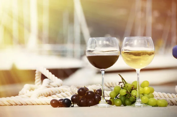 Pair of wineglasses and grapes against the yacht pier — Stock Photo, Image
