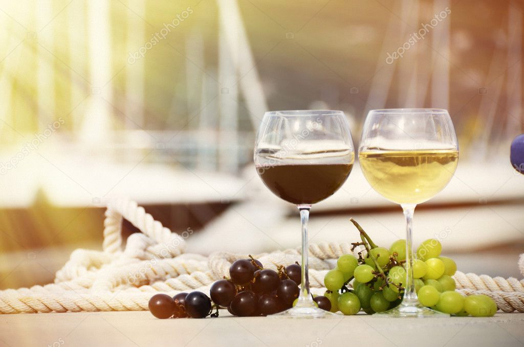 Pair of wineglasses and grapes against the yacht pier