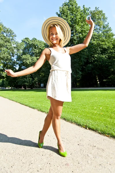 Vacker ung kvinna med hatt i park med stora sexiga leende — Stockfoto