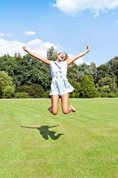 Schöne junge Frau springt im Park in den Himmel — Stockfoto