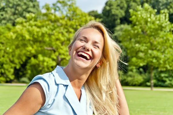 Güzel bir genç kadın saçlarını oynarken parkta yeşil loawn üzerinde bir — Stok fotoğraf