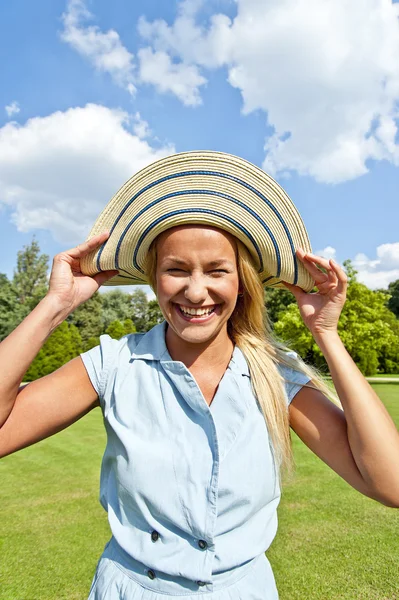 Schöne junge Frau mit Hut im Park mit großem freudigem Lächeln — Stockfoto