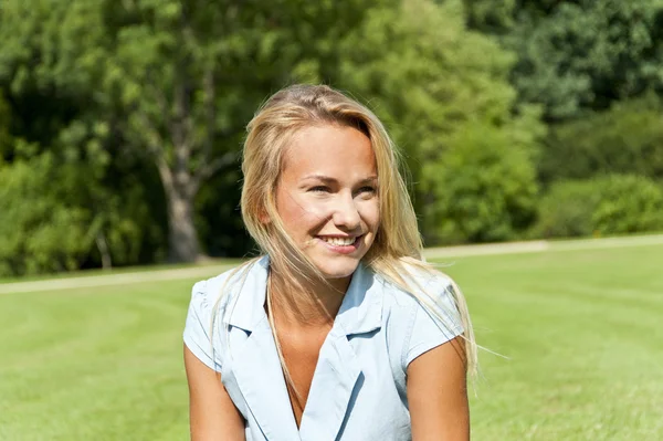 Beautiful young woman in park with big sensual smile over the gr Royalty Free Stock Images