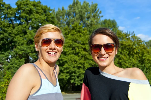 Deux belles femmes avec des lunettes de soleil sur fond naturel — Photo