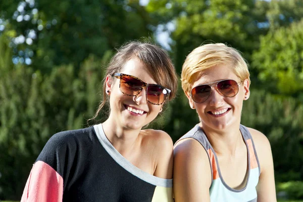 Две красивые женщины в солнечных очках в парке — стоковое фото