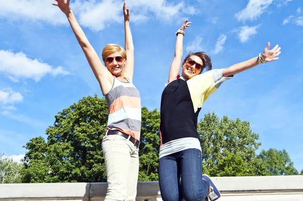 Belles jeunes deux filles en saut par-dessus le ciel bleu — Photo