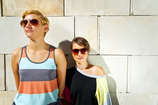 Deux belles femmes avec des lunettes de soleil fond de mur en pierre — Photo