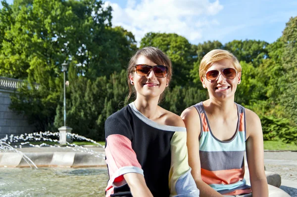 Dos hermosas mujeres con gafas de sol en el parque —  Fotos de Stock