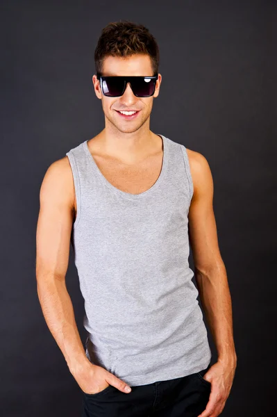 Hombre guapo en camiseta gris con sonrisa y gafas de sol —  Fotos de Stock