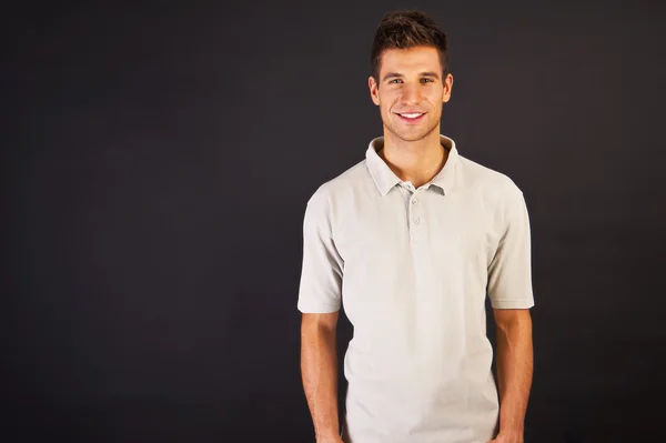 Man i grå polo t-shirt på svart backgraund med leende — Stockfoto