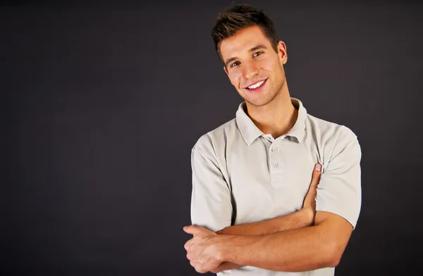 Man in grijs polo t-shirt op zwarte backgraund met glimlach Rechtenvrije Stockfoto's