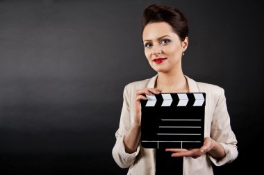 Woman with movie clap over black background