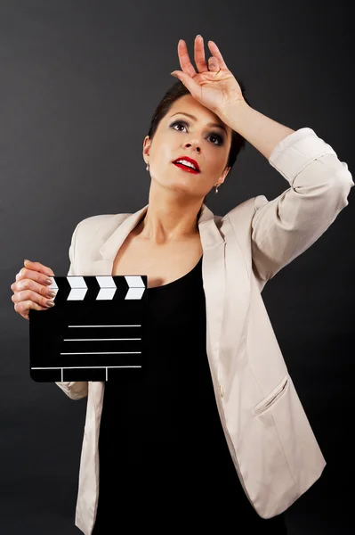 Woman with movie clap over black background — Stockfoto