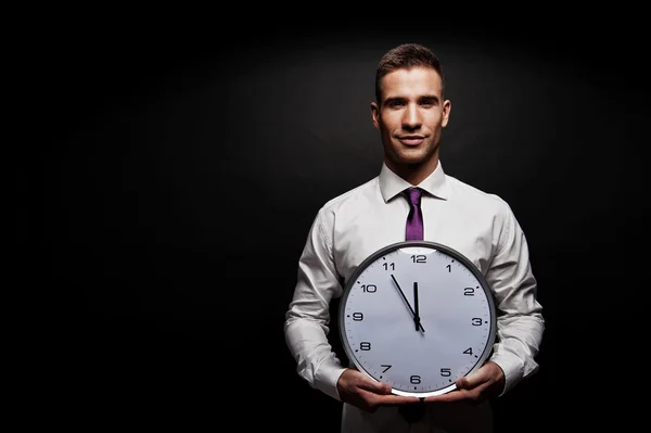 Man with wall clock over dark background — Stock Photo, Image