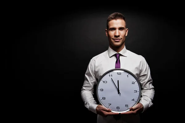 Uomo con orologio da parete su sfondo scuro — Foto Stock