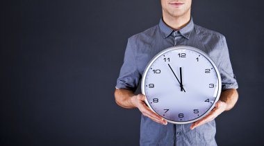 duvar saati koyu arka plan üzerinde tutan adam