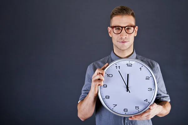 Uomo tenendo orologio da parete su sfondo scuro — Foto Stock