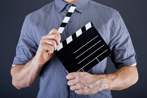 Mann mit Filmklappe vor dunklem Hintergrund — Stockfoto