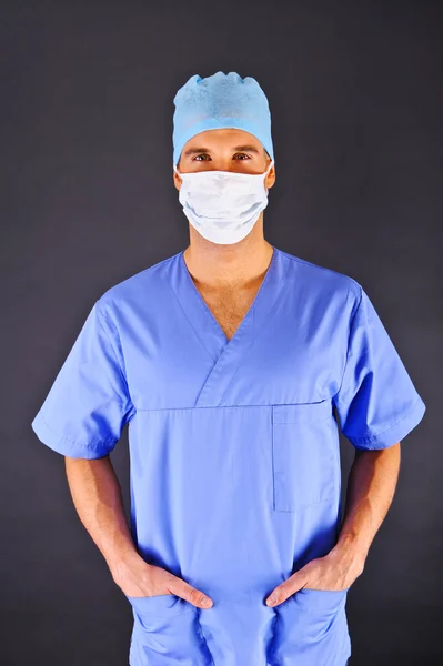 Doctor over dark background in blue shirt — Stock Photo, Image
