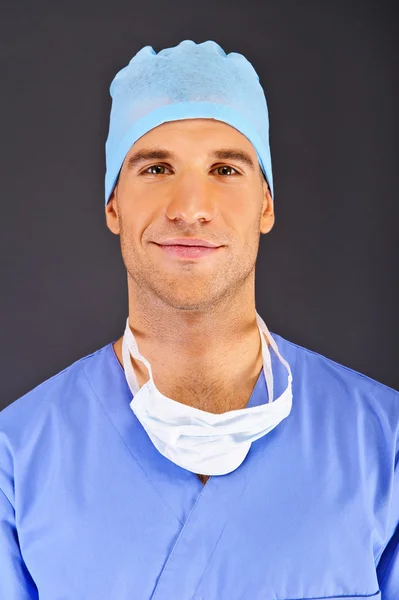 Doctor over dark background in blue shirt — Stock Photo, Image