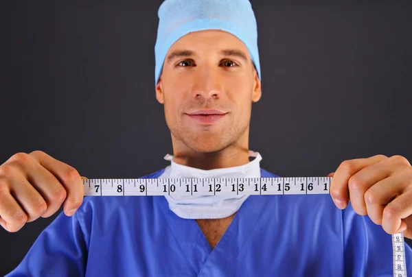 Chirurg mit Zentimeter über dunklem Hintergrund — Stockfoto