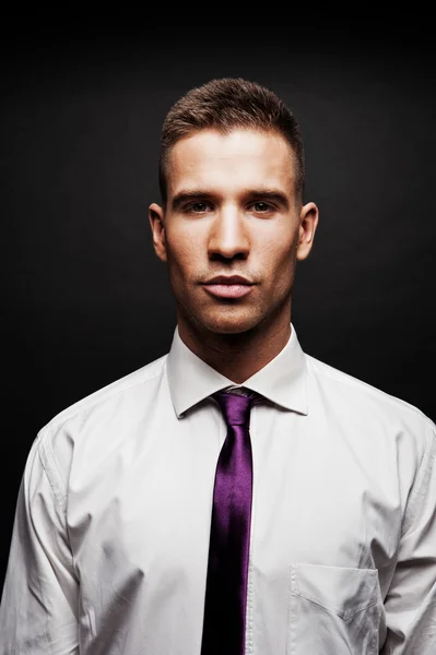 Homem com gravata roxa sobre fundo escuro — Fotografia de Stock
