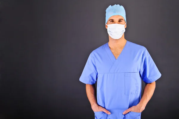 Doctor over dark background in blue shirt — Stock Photo, Image