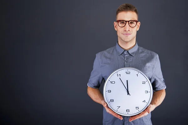 Hombre sosteniendo reloj de pared sobre fondo oscuro —  Fotos de Stock