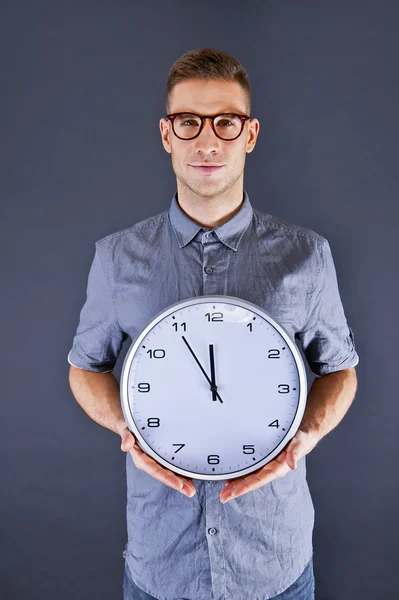 Uomo tenendo orologio da parete su sfondo scuro — Foto Stock