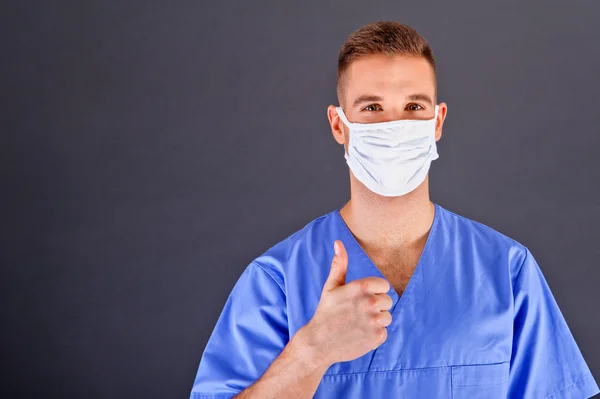 Surgeon with thumb up over dark background — Stock Photo, Image