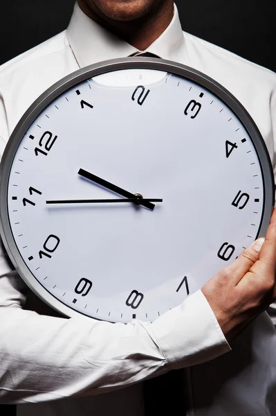 Man with wall clock over dark background — Stock Photo, Image