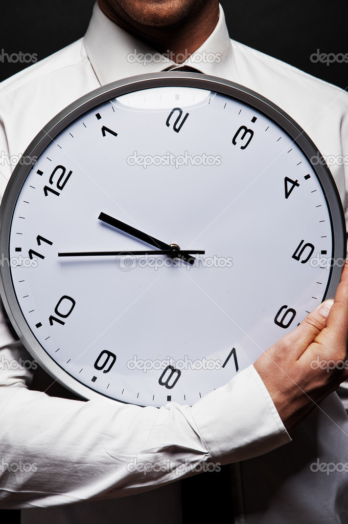 Man with wall clock over dark background