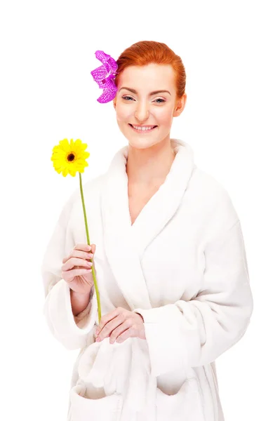 Kobieta w szlafrok uśmiechający się z kwiatem — Zdjęcie stockowe