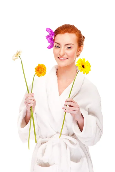 Woman in bathrobe smiling with flowers — Stock Photo, Image