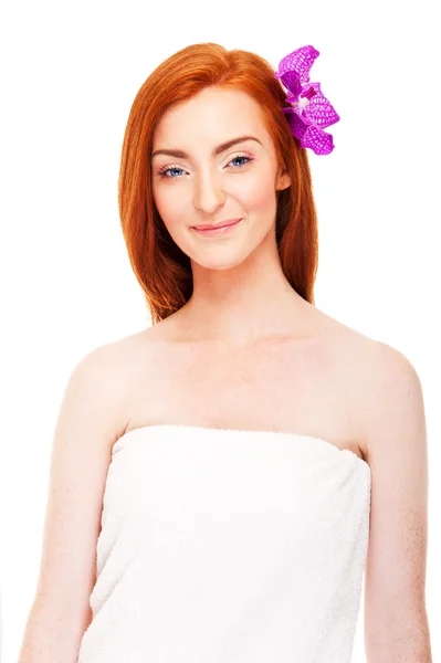 Nainen valkoisessa pyyhkeessä ja kukka hiuksissa — kuvapankkivalokuva