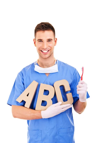 Retrato del dentista masculino feliz con letras y cepillo de dientes —  Fotos de Stock