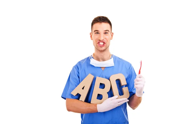 Portrait of happy male dentist with letters and toothbrush — Stock Photo, Image