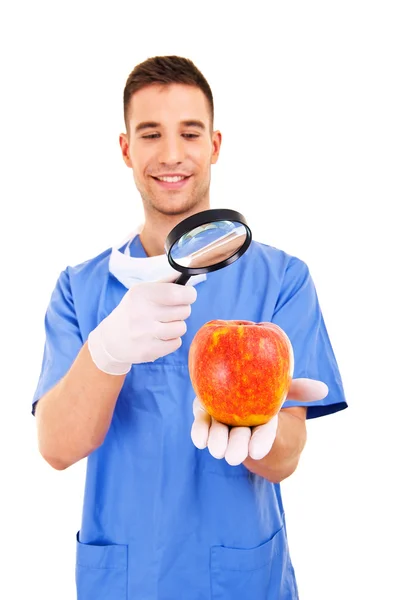 Doctor in blue apron holding red healthy apple — Stock Photo, Image