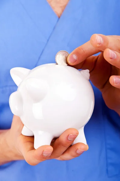 Male Doctor Putting Coins In A Piggy Bank — Stock Photo, Image