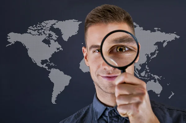 Man with magnifier and world map on dark background — Stok Foto