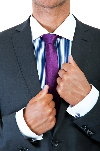 Hombre de negocios corrigiendo una corbata sobre fondo negro — Foto de Stock