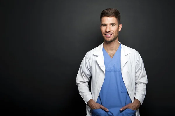 Portrait of confident young medical doctor on dark background — Stock Photo, Image