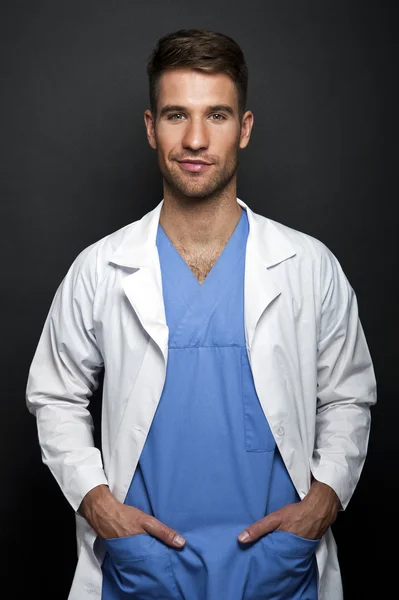 Portrait of confident young medical doctor on dark background — Stock Photo, Image